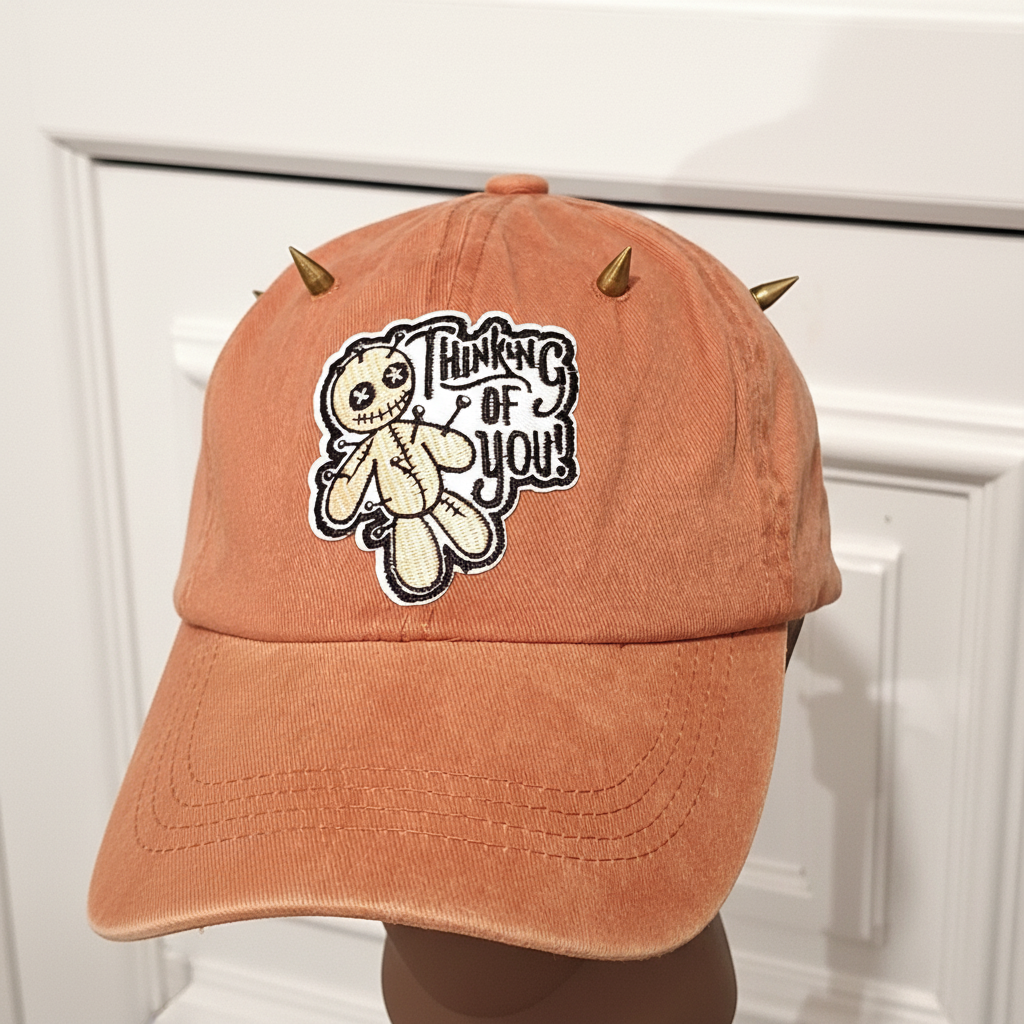 Front angle view of orange denim cap with gold spikes and patch